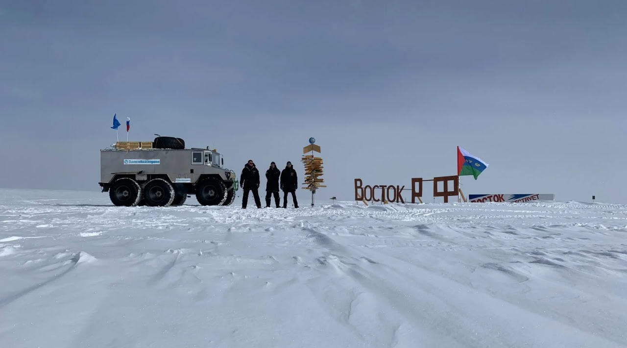 Ученые с машиной у названия станции в Антарктике